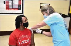  ?? (Pine Bluff Commercial/I.C. Murrell) ?? Kayle Williams, 17, a junior at Watson Chapel High School, gets her first covid-19 shot from campus registered nurse Tiffany Eichler during school Thursday.