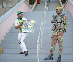  ?? Picture: Reuters ?? SHOW OF SUPPORT. A Zanu-PF supporter holds a poster in front of a soldier ahead of a rally in Harare on Saturday.