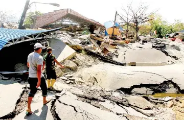  ??  ?? People walk in an area hit by an earthquake in Petabo, South Palu in this photo taken by Antara Foto. — Reuters photo