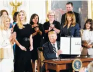  ?? THE ASSOCIATED PRESS ?? President Donald Trump holds up an executive order he signed Wednesday in the White House during an event celebratin­g military mothers and spouses. Among those with him are, from left, counselor to the president Kellyanne Conway; Ivanka Trump; first...