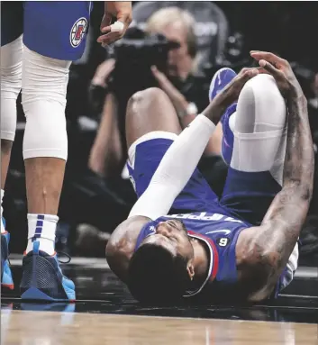  ?? AP PHOTO/RINGO H.W. CHIU ?? Los Angeles Clippers forward Paul George (right) lies on the court after an injury during the second half of the team’s NBA basketball game against the Oklahoma City Thunder on Tuesday in Los Angeles.