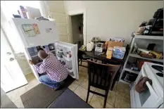  ?? AP photo ?? Norman Butler unboxes food that he received at a food distributi­on point in his apartment after waiting in line overnight in New Orleans on Nov. 19. Before the pandemic, Butler, 53, flourished in the tourism-dominated city, working as an airport shuttle and limousine driver, a valet and hotel doorman. Since March when the normally bustling streets turned silent, the only work he’s had has been as an Uber driver.