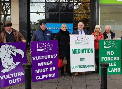  ??  ?? Members of the ICSA highlighti­ng vulture fund sales of indebted farms online outside the offices of BidX1 yesterday