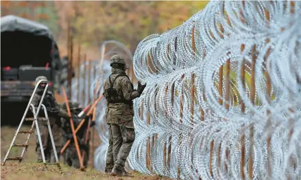  ?? MICHAL KOSC/AP ?? Polish soldiers erect a razor-wire barrier along their national border with the Russian exclave of Kaliningra­d on Nov. 2 in Wisztyniec, Poland.