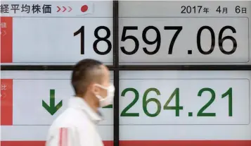  ?? — AFP ?? A man walks past a stock quotation board flashing the Nikkei 225 key index of the Tokyo Stock Exchange in front of a securities company in Tokyo on April 6, 2017.