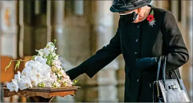  ??  ?? TOUCHING: The Queen reaches out to her bouquet before it is laid on to the grave of the Unknown Warrior