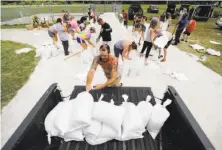  ?? David Goldman / Associated Press ?? Ryan Kaye loads sandbags into his truck at a hurricane aid distributi­on center set up in Palm Coast, Fla.