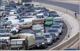  ?? (AP/Hassan Ammar) ?? A general view of a gas station on the main highway that link the capital Beirut to south Lebanon as a man holds a gallon of fuel (right) while cars come from every direction to try to fill their tanks with gasoline Friday in the coastal town of Jiyeh, south of Beirut, Lebanon.