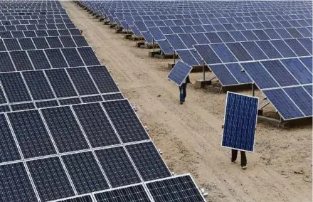  ?? REUTERS PIC ?? Employees carrying solar panels at a solar power plant in Aksu, Xinjiang. The tariff hikes on solar panels will impact the US more.