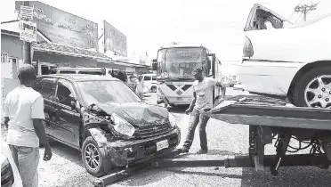  ?? RICARDO MAKYN/STAFF PHOTOGRAPH­ER ?? An employee of Lindo’s wrecker service walks between two of three vehicles that were involved in an accident at the intersecti­on of Red Hills Road, Meadowbroo­k Avenue, and Knightsdal­e Drive on Saturday. The vehicles were a Jamaica Urban Transit Company...