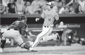  ?? NICK WASS/ASSOCIATED PRESS ?? The Orioles’ Trey Mancini scores past catcher Jesus Sucre on a double by Joey Rickard during the sixth inning. Rickard has 18 RBIs this season — 13 of them against Tampa Bay.