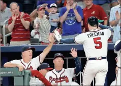  ?? John Bazemore / AP ?? Atlanta’s Freddie Freeman (5) is greeted at the dugout by hitting coach Kevin Seitzer (left) and manager Brian Snitker after hitting a three-run home run.