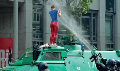  ??  ?? Il simbolo Una manifestan­te sale su una camionetta della polizia ad Amburgo, durante il G20, e viene colpita dagli idranti