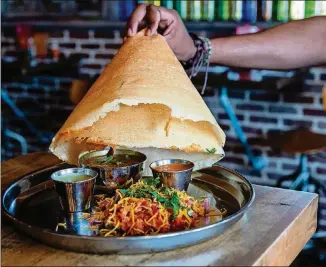  ?? CONTRIBUTE­D BY HENRI HOLLIS ?? The Bollywood Masti at Indian street food restaurant Masti includes a hat-shaped dosa served over butter chicken, tomato stew and two chutneys for dipping.