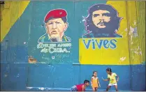  ?? RAMON ESPINOSA / AP ?? Children play in a Havana street beneath an image of Venezuela’s former President Hugo Chavez, captioned “Best friend of Cuba,” and revolution­ary Ernesto “Che” Guevara on Tuesday.