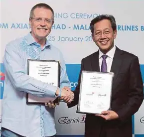  ?? PIC BY NIK HARIFF HASSAN ?? Celcom Axiata Bhd chief executive officer (CEO) Michael Kuehner (left) exchanging documents with Malaysia Airlines Bhd CEO Capt Izham Ismail after the signing of a memorandum of understand­ing in Kuala Lumpur yesterday.