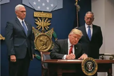  ??  ?? US President Donald Trump signs an executive order alongside Defense Secretary James Mattis and Vice President Mike Pence on January 27, 2016, to begin what he called a “great rebuilding” of the US armed services, promising new aircraft, naval ships...