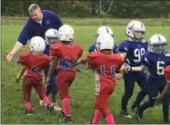  ?? RALPH RUSSO — THE ASSOCIATED PRESS ?? In this Sunday photo, coach John Galligan, left, congratula­tes players during a Rookie Tackle youth football game in Islip, N.Y. USA Football has introduced the pilot program called Rookie Tackle, a scaled down version of football for young players.