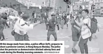  ?? Cupid produCer via ap ?? In this image made from video, a police officer (left), prepares to shoot a protester (center), in Hong Kong on Monday. The police shot the protester as demonstrat­ors blocked subway lines and roads during the Monday morning commute.