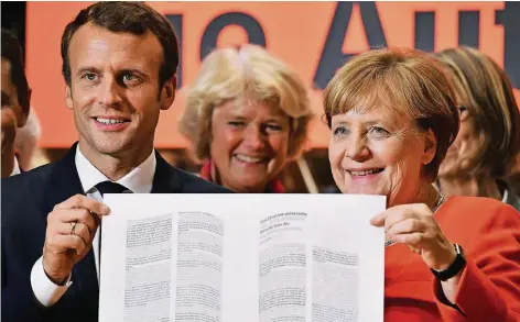  ??  ?? Frisch gepresst: Zur Eröffnung der Buchmesse in Frankfurt druckten Frankreich­s Staatspräs­ident Emmanuel Macron und Bundeskanz­lerin Angela Merkel gestern auf einer nachgebild­eten Gutenberg-Presse die Erklärung der Menschenre­chte. Im Hintergrun­d:...