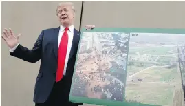  ??  ?? U.S. President Donald Trump holds a photo of the Mexican border area as he reviews wall prototypes Tuesday in San Diego.