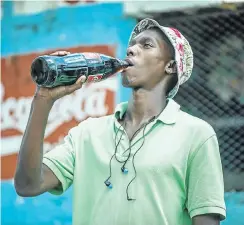  ?? Picture: AFP ?? A resident of Zandspruit, Johannesbu­rg, drinks from a bottle of Coke. This week CocaCola Beverages SA launched a foundation to support black farmers.