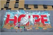  ?? AP PHOTO/BILAL HUSSEIN ?? On Monday, women walk past a graffiti “Hope” painted on metals barrier that closed the entrance of a hotel that was damaged by an Aug. 4 explosion that hit the seaport of Beirut, Lebanon.