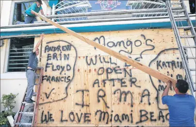  ?? AP PHOTO ?? Workers shutter Mango’s Tropical Cafe in Miami Beach, Fla., Thursday.