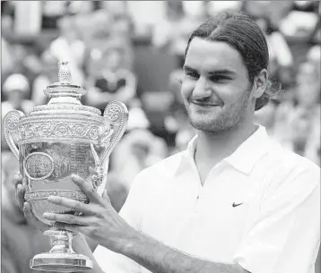  ?? DAVE CAULKIN/AP ?? The championsh­ip trophy Roger Federer held in 2003 was his first one at Wimbledon. He has since claimed seven others.