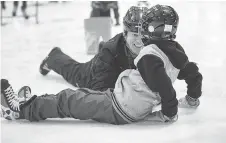  ??  ?? Ruggles Pritchard has a laugh with a skater who fell during a skating session for grades 3, 4 and 5 students.