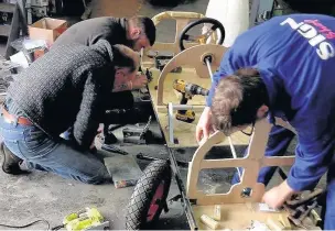  ??  ?? Pictured are members of the team working on a steel chassis and wooden space-frame - which forms the car’s shape.