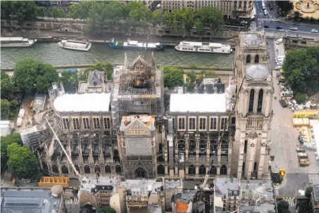  ?? Lionel Bonaventur­e / AFP / Getty Images ?? Tarps cover the roof of Notre Dame on Wednesday during repairs to the church, which was severely damaged by an April 15 fire.