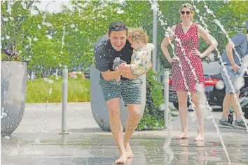  ?? SHURAN HUANG/THE NEW YORK TIMES ?? A father and daughter run through fountains at The Wharf developmen­t Saturday in Washington. Roughly a third of Americans will see a chillier-than-usual May yield to midsummer-like temperatur­es this weekend.