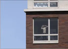  ?? BRIAN W. KRATZER — MISSOURIAN VIA AP ?? A resident of a downtown apartment complex glances out of his window Monday as the eclipse begins over Columbia, Mo.