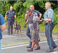  ?? SEAN D. ELLIOT THE DAY ?? Police escort a bank robbery suspect out of the woods behind the former Toys R Us in Waterford on Wednesday. Police pursued two suspects from the Navy Federal Credit Union on Sailfish Drive in Groton, catching one with the vehicle and the other...