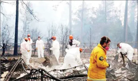  ?? REUTERS ?? A volunteer search and rescue team combing a home destroyed by the California wildfire in Paradise.