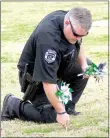  ?? Photo by Randy Moll ?? Officer Charles Strickland of the Gentry Police Department assisted members of the Gentry High School student council in placing pinwheels on the lawn at Gentry Police Station on Friday.