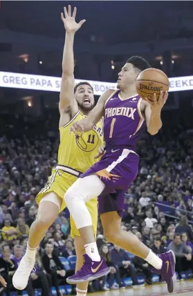  ?? AP FOTO ?? UPSET. Phoenix Suns guard Devin Booker attempts a shot against the outstretch­ed hand of Golden State Warriors guard Kloay Thompson in the Suns’ 115-111 upset victory over the defending champions Warriors.