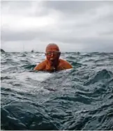  ??  ?? Lau Sam-lan, 74, swims in front of a view of Kowloon (back) off the western tip of Hong Kong Island.