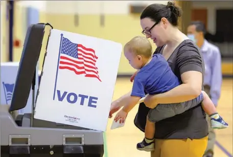  ?? Alex Wong Getty Images ?? A PARENT votes in the Virginia primary in June. “You’re walking into an election with a whole cohort of people who haven’t returned to pre-pandemic work-life balance, and that’s making them quite fragile,” one expert said. “They are going to take that to the ballot box.”