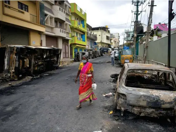  ?? (Manjunath Kira/Getty) ?? A woman walks past burned out cars in Bengaluru, India, yesterday