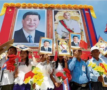  ?? – Reuters ?? Warm welcome: Cambodians standing next to portraits of Xi (left) and King Norodom during Xi’s welcoming ceremony at Phnom Penh, Cambodia.