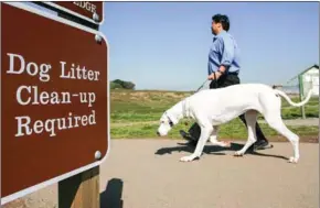  ?? AFP ?? A dog and its owner walk by a sign about litter clean-up in San Francisco.