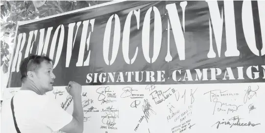  ??  ?? REMOVE. A concerned citizen of Cagayan de Oro, on Wednesday, is about to sign his signature in a tarpaulin situated in Press Freedom Monument in Capitol grounds of Misamis Oriental, calling for the removal of Council Zaldy Ocon from his elective post, after having a verbal scuffle with former mayor Reuben Canoy at a hotel last week. Ocon asks for apology to Canoy through Monday's city council session. (PJ ORIAS)
