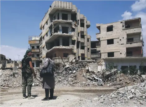  ?? AFP ?? A Syrian soldier with a woman yesterday on a destroyed street in the former rebel-held town of Zamalka in Eastern Ghouta, on the outskirts of the capital Damascus. A chemical attack in the region has prompted the US to threaten military action