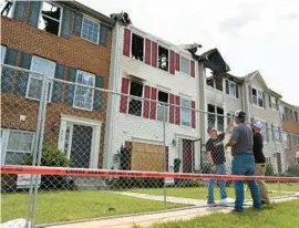  ?? ?? Workers from Thomasvill­e Restoratio­n set up a fence around the perimeter of the damaged group of town homes. It took about 60 firefighte­rs from several fire companies almost two hours to control Monday’s blaze.