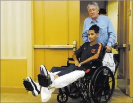  ?? Marta Lavandier ?? The Associated Press Anthony Borges is pushed by his grandfathe­r Alfredo Borges at the start of a news conference Friday in Plantation, Fla. Borges sustained five bullet wounds after he used his body to block a classroom door during the Feb. 14 massacre in Parkland, Fla.