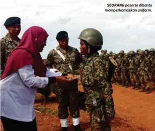  ??  ?? SEORANG peserta dibantu memperkema­skan uniform.