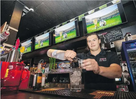  ?? LIAM RICHARDS ?? Bartender Brandon Molinger pours a drink at Sports on Tap on Wednesday while World Cup coverage plays on TVS behind him. While Sport on Tap is not among them, some local watering holes will offer extended hours during the World Cup, which is being...