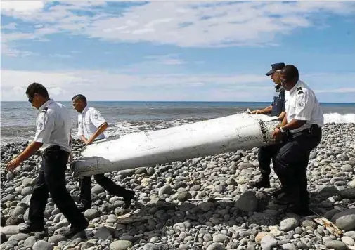  ?? Foto: Raymond Wae Tion/MAXPPP/QUOTIDIE ?? Techniker tragen ein Wrackteil, die Flügelklap­pe eines Flugzeugs, über einen Strand bei Saint-Andre de la Reunion. An diesem Freitag jährt sich zum zehnten Mal das Verschwind­en der Boeing-Maschine, mit 239 Menschen an Bord.